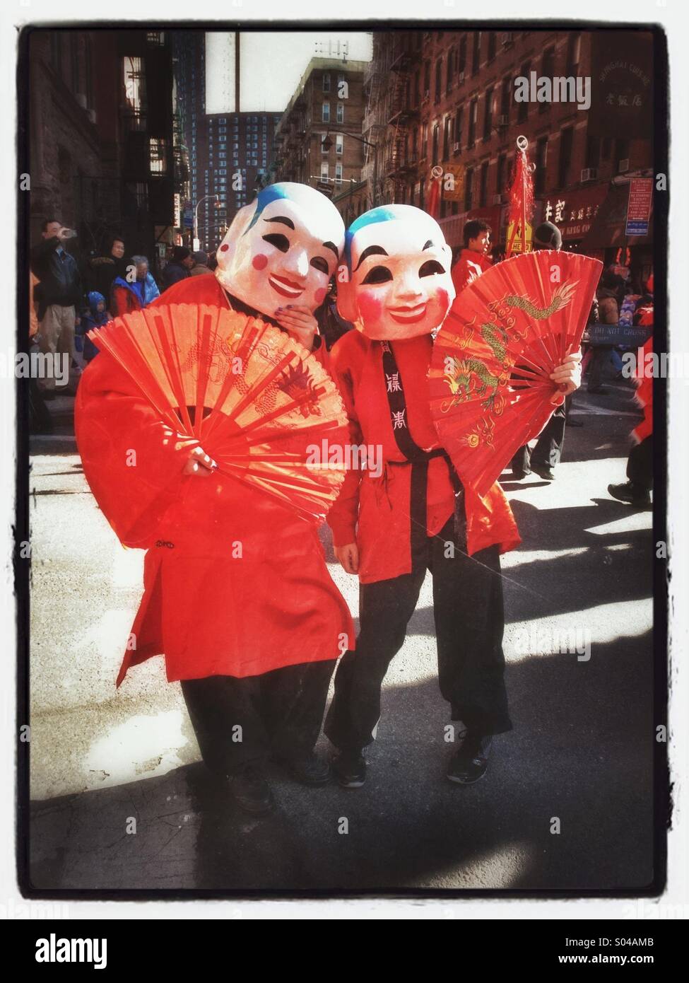Deux personnes avec des masques de cérémonie et des supporters à la célébration du nouvel an chinois à New York Banque D'Images