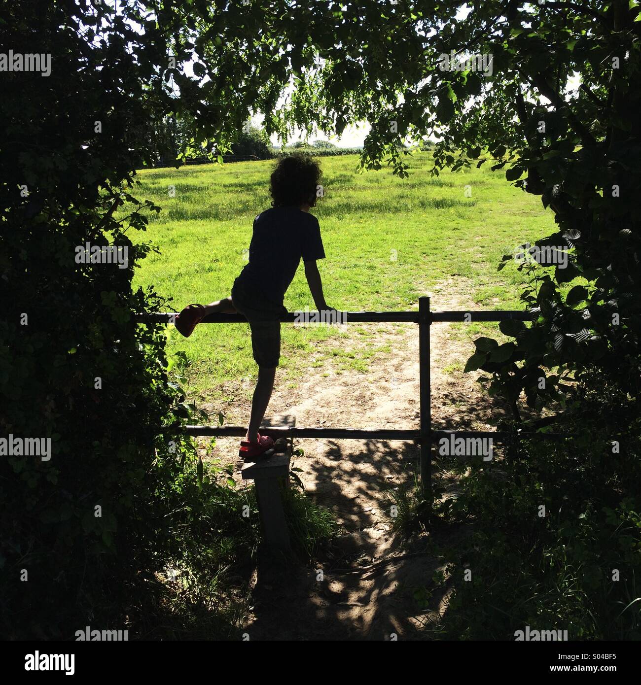Silhouette de jeune fille traversant un stile sur un chemin du pays dans l'East Sussex Banque D'Images