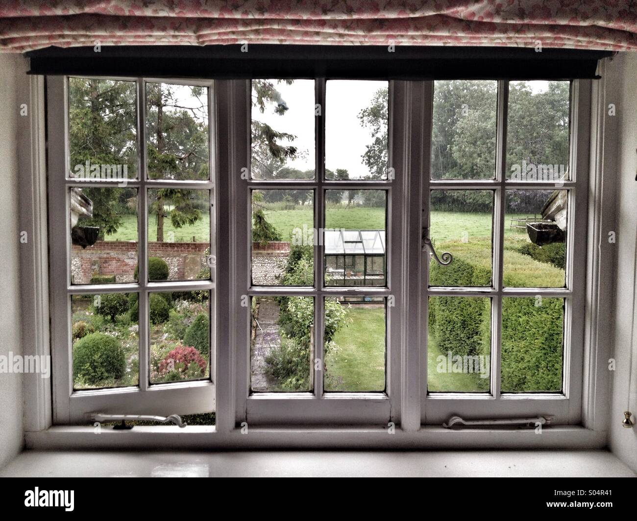 Vue depuis une fenêtre sur un jardin anglais. Banque D'Images