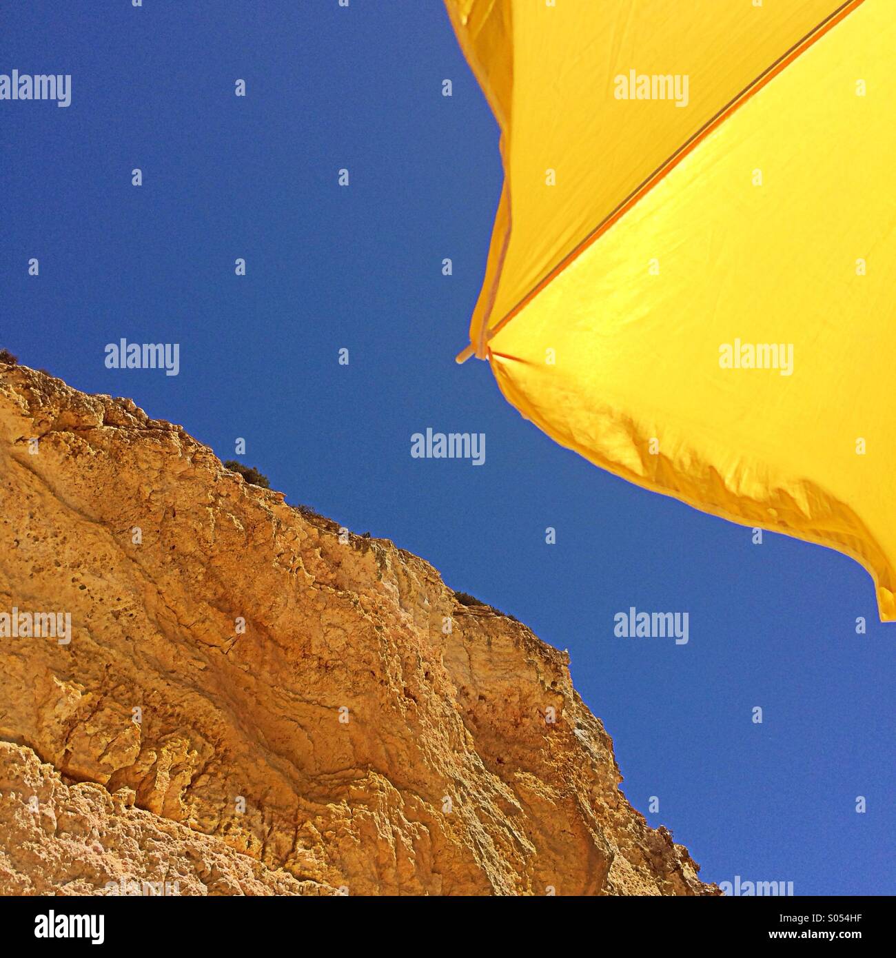 Parasol jaune, ciel bleu et des roches, Algarve, Portugal Banque D'Images
