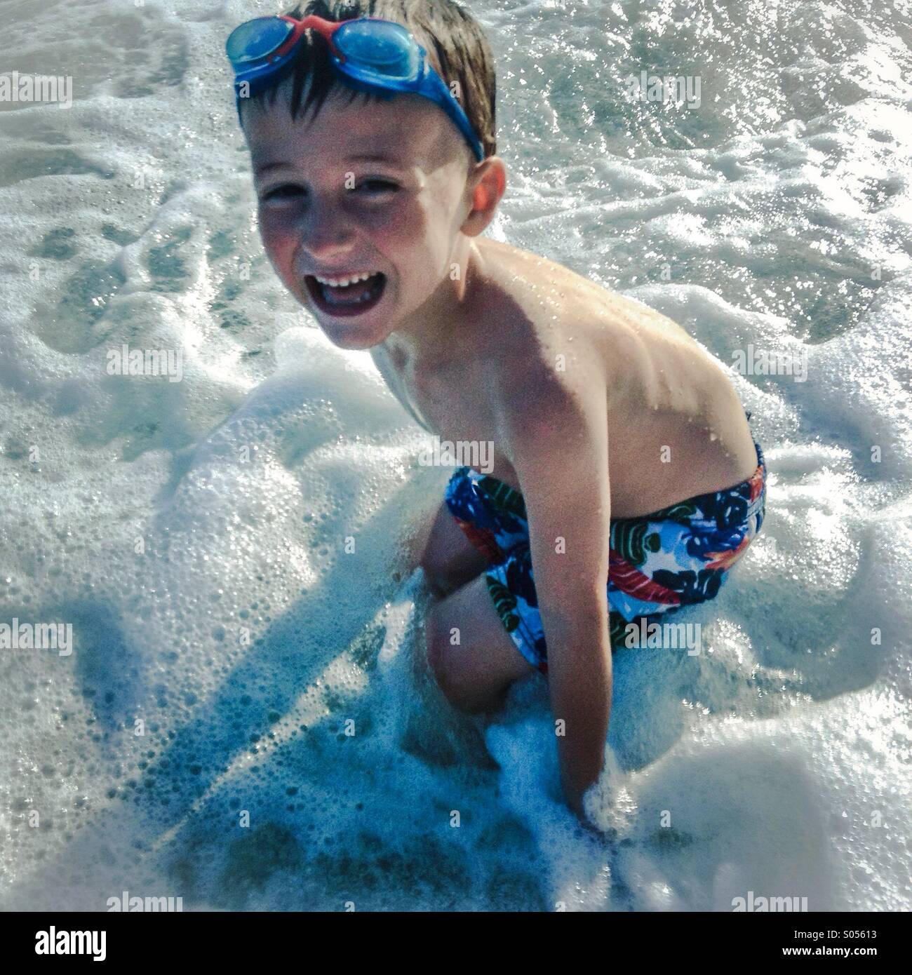 Un garçon jouant dans les vagues sur la plage de Sant Pol de Mar, el Maresme, Barcelone, Espagne Banque D'Images