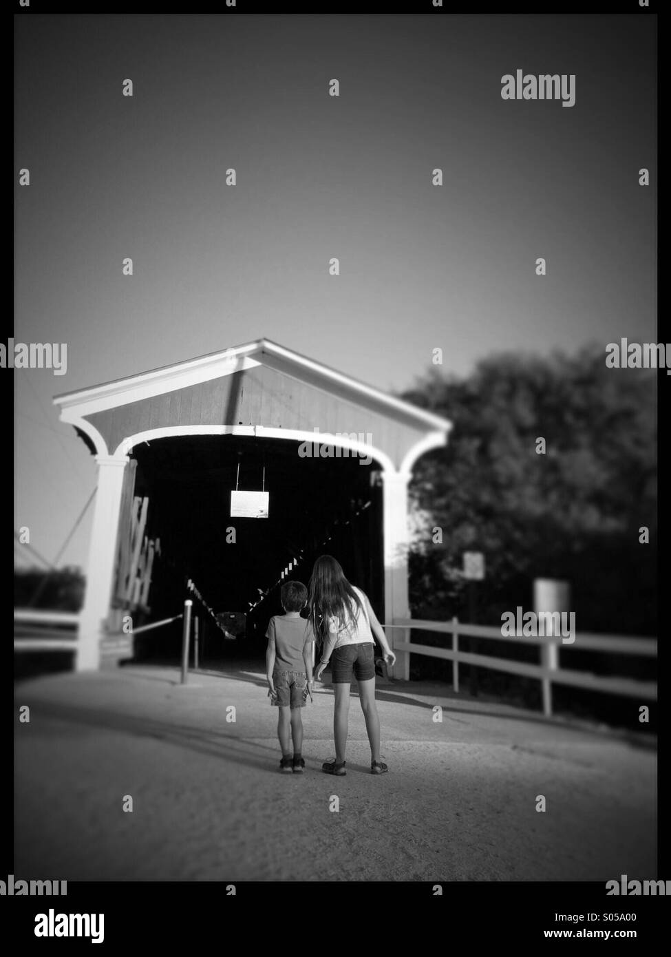 A 10 ans, fille et garçon de 6 ans, regarder dans un vieux pont couvert. Knights Ferry, California, USA Banque D'Images