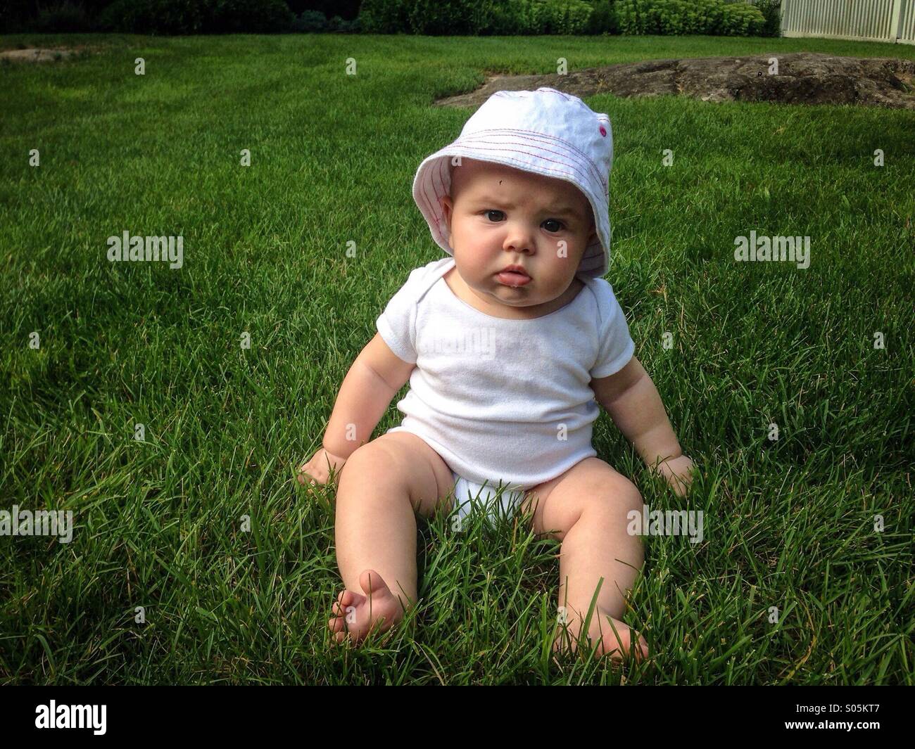 Bébé âgé de 5 mois assis bien droit sur l'herbe verte Banque D'Images
