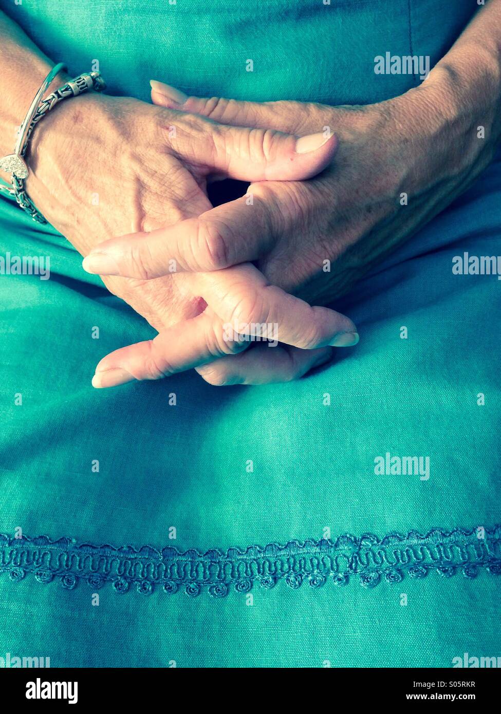 Woman's hands clasped dans lap Banque D'Images