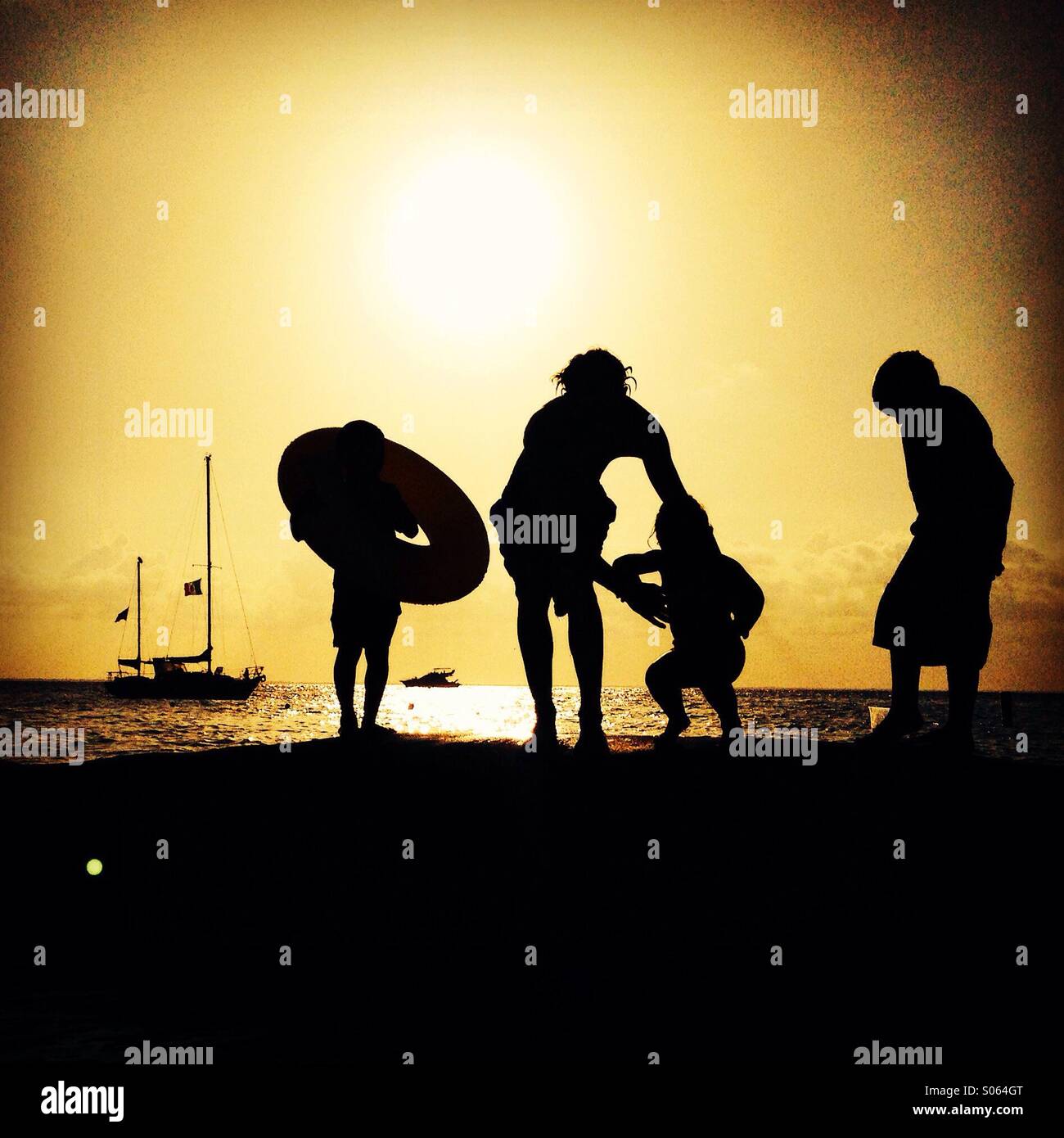 Silhouette de quatre personnes au coucher du soleil sur la mer Banque D'Images