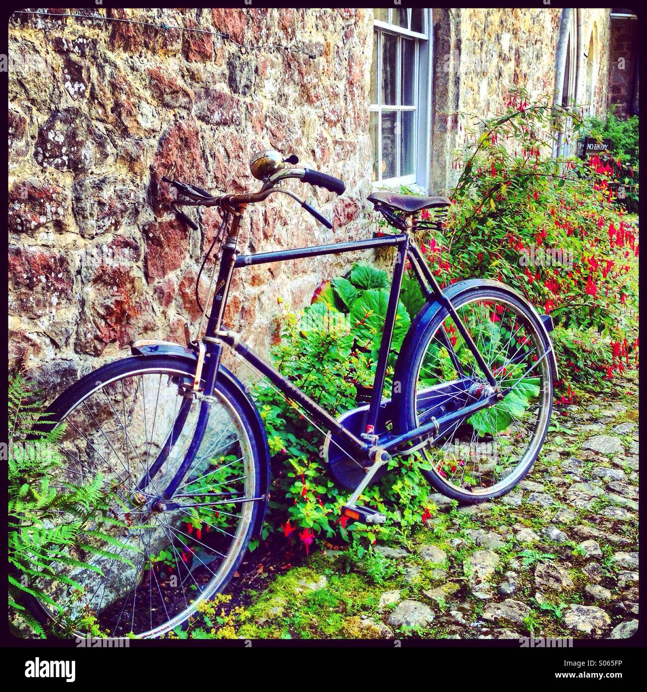 Un vélo appuyé contre le mur d'une maison en pierre. - Image de stock capturée avec un smartphone