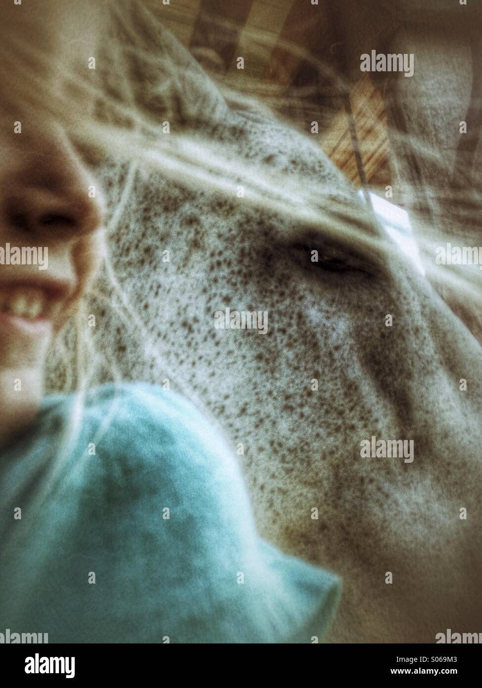 Une jeune fille les cheveux au vent comme elle sourit à un cheval. Banque D'Images