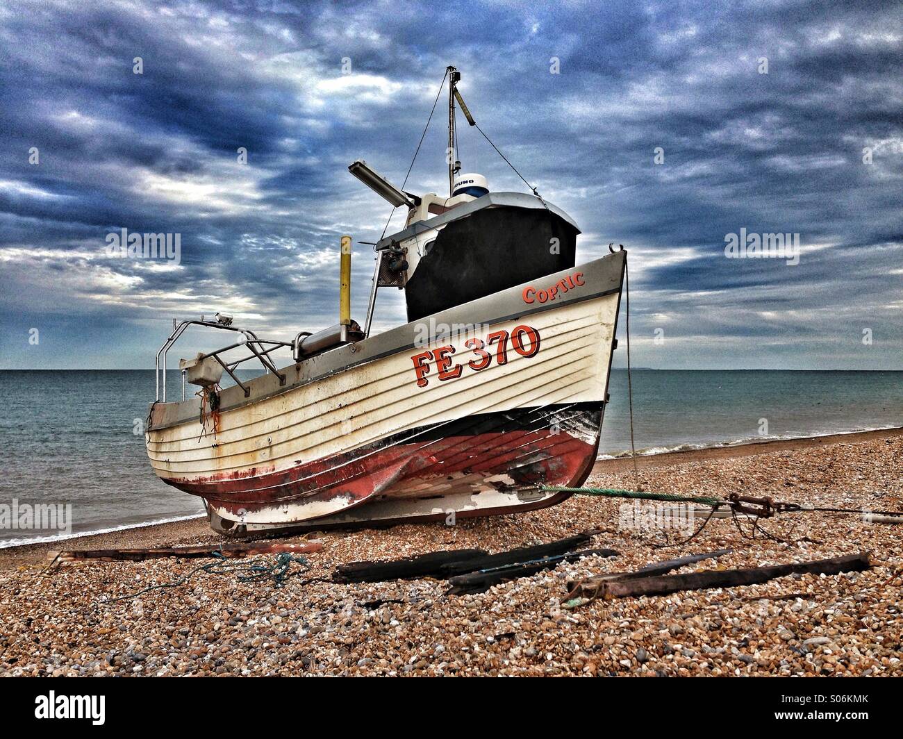 Photo HDR d'un vieux bateau sur une plage de galets avec de gros nuages dans le ciel de brassage. Crédits photos - © COLIN HOSKINS. Banque D'Images
