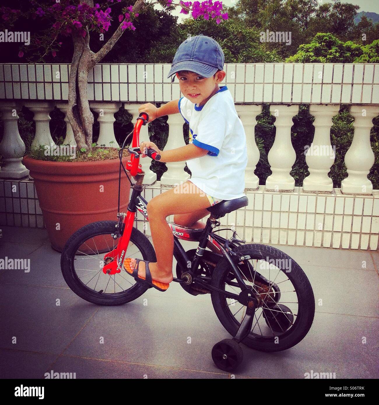 Petit garçon eurasien est à vélo avec son vélo sur une terrasse Banque D'Images