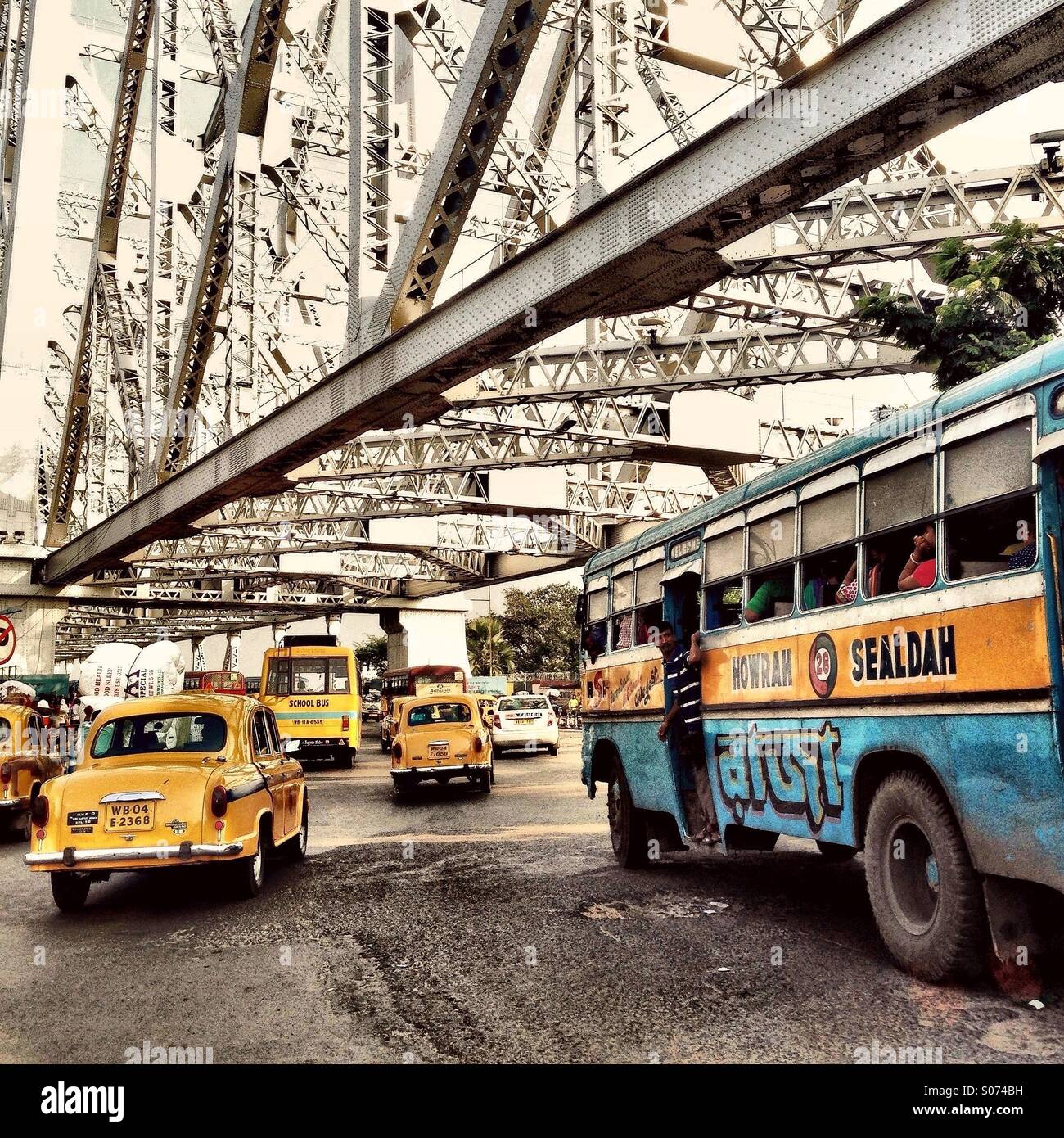 Taxis et bus crossing Howrah Bridge, Kolkata, Inde Banque D'Images