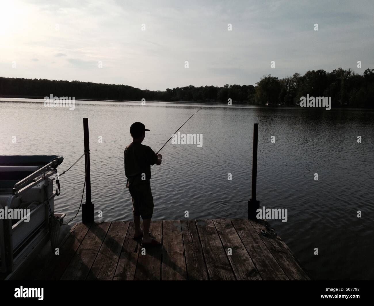 Silhouette de garçon de pêche à partir d'un dock. Banque D'Images