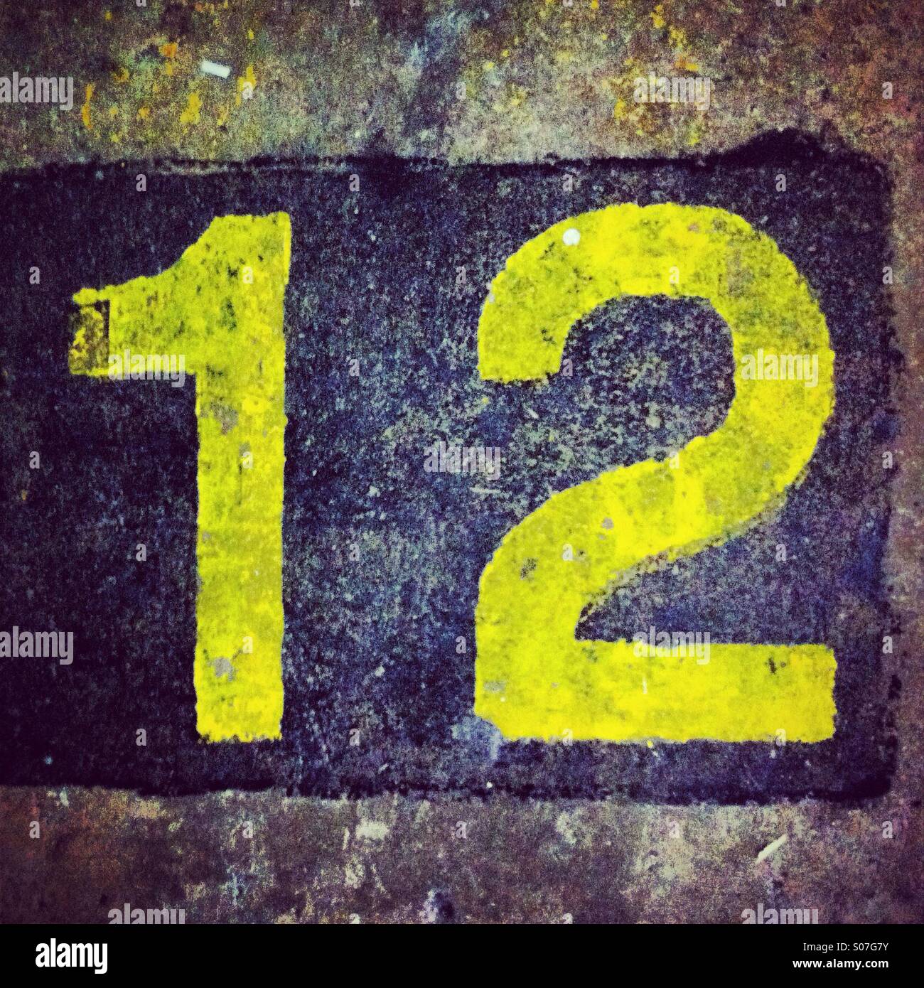 Numéro douze dans la couleur jaune sur le sol rugueux Banque D'Images