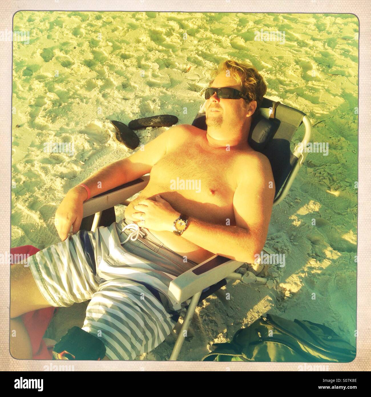 Homme étendu dans sun chaise de plage Banque D'Images