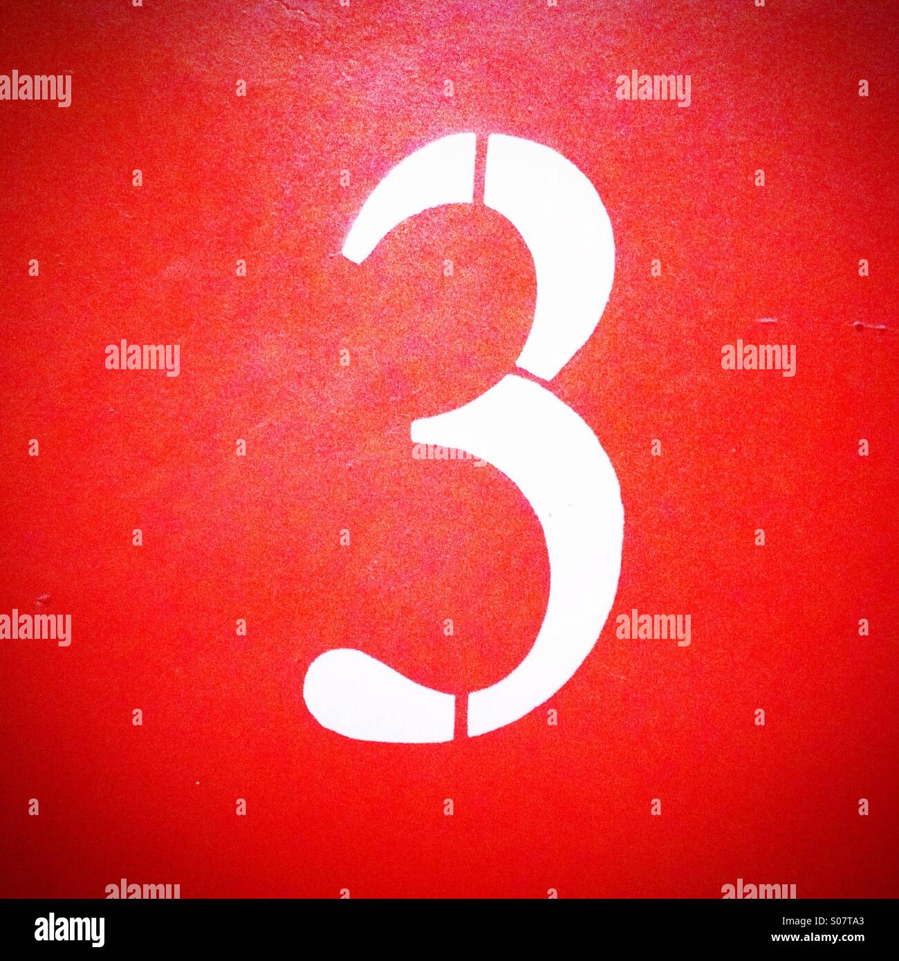 Numéro 3 peint en blanc sur le mur orange - Image de stock capturée avec un smartphone