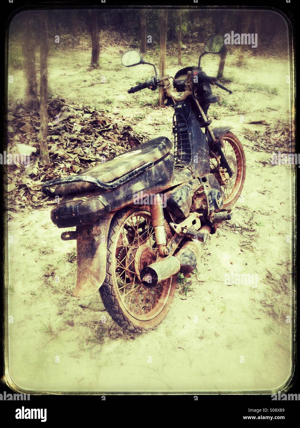 Rusty old moto garée dans un village de Thaïlande Banque D'Images