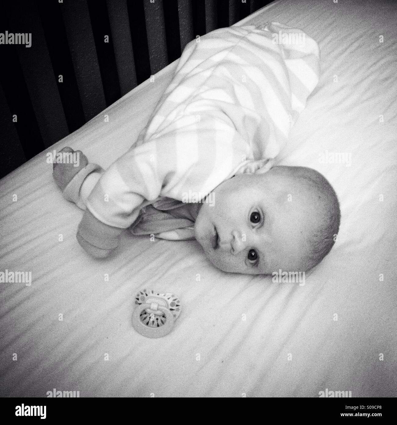 Photo en noir et blanc d'un petit garçon pose dans un lit de bébé Banque D'Images
