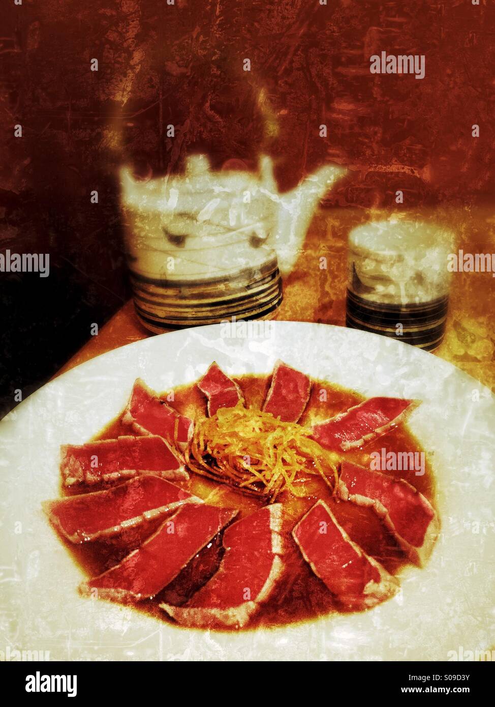 Grunge textured color photo d'un tataki de thon avec sauce Ponzu apéritif et Japonais théière et tasse sur une table dans un restaurant. Banque D'Images