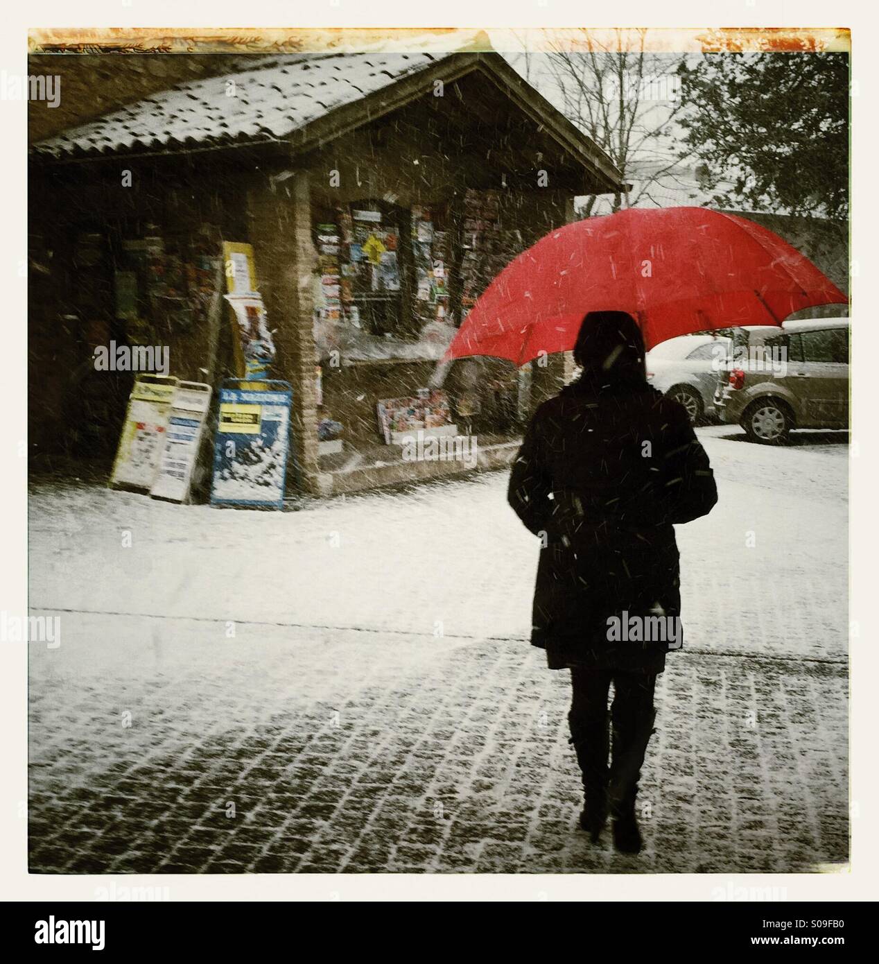 Femme vue de l'arrière avec un parapluie rouge dans la neige Banque D'Images