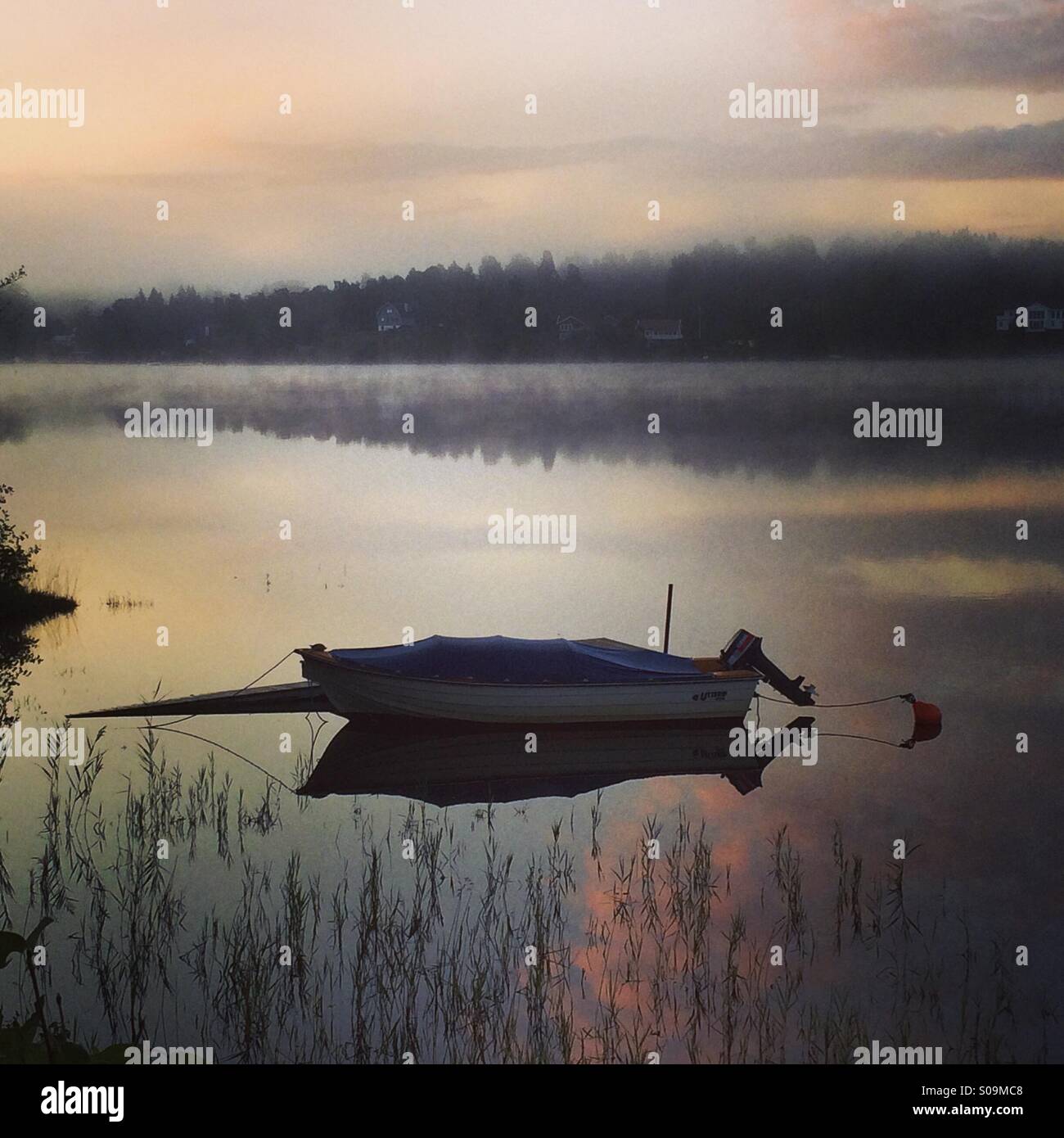 Bateau sur un lac encore comme un miroir dans le brouillard du matin. - Image de stock capturée avec un smartphone