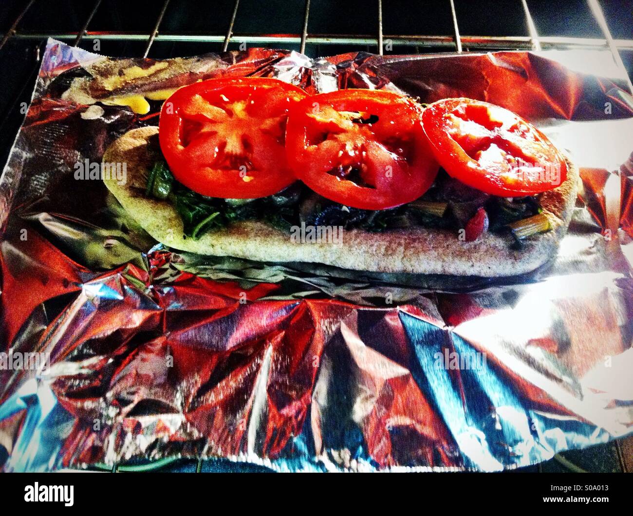 Sandwich de pain naan ouvert prêt pour la cuisson au four sur une feuille d'aluminium brillant Banque D'Images