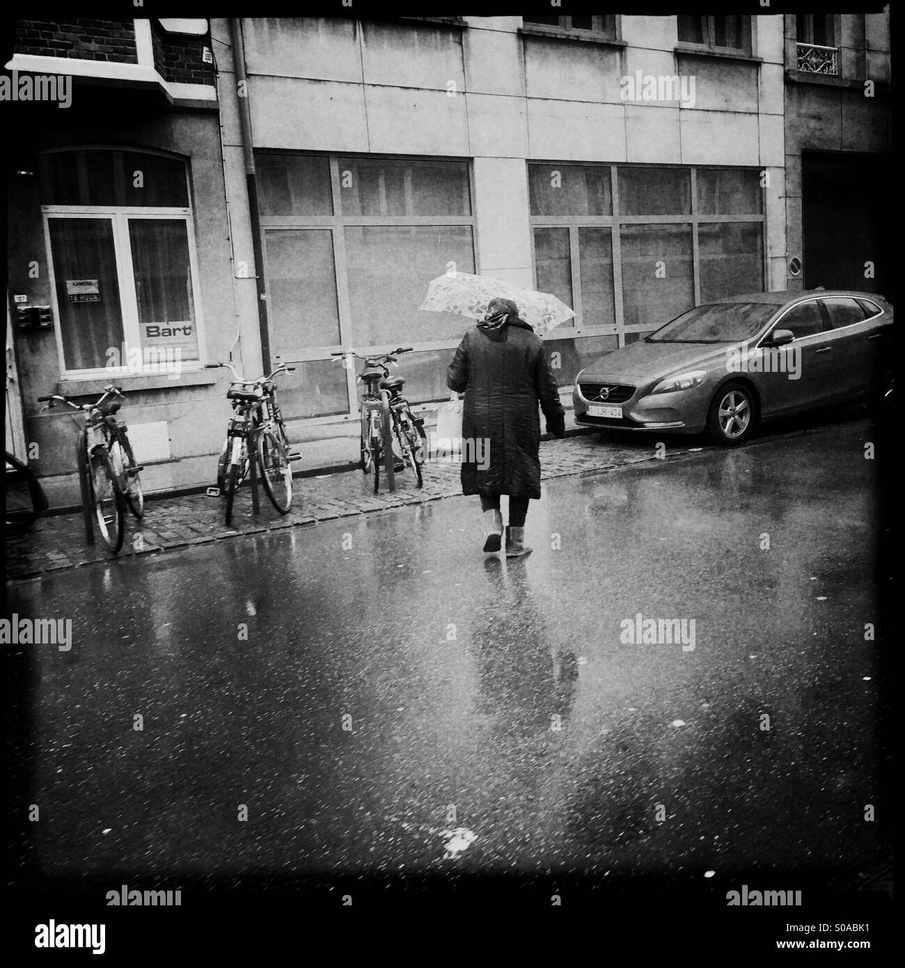 Vieille dame traversant la rue un jour de pluie à Leuven, Belgique Banque D'Images