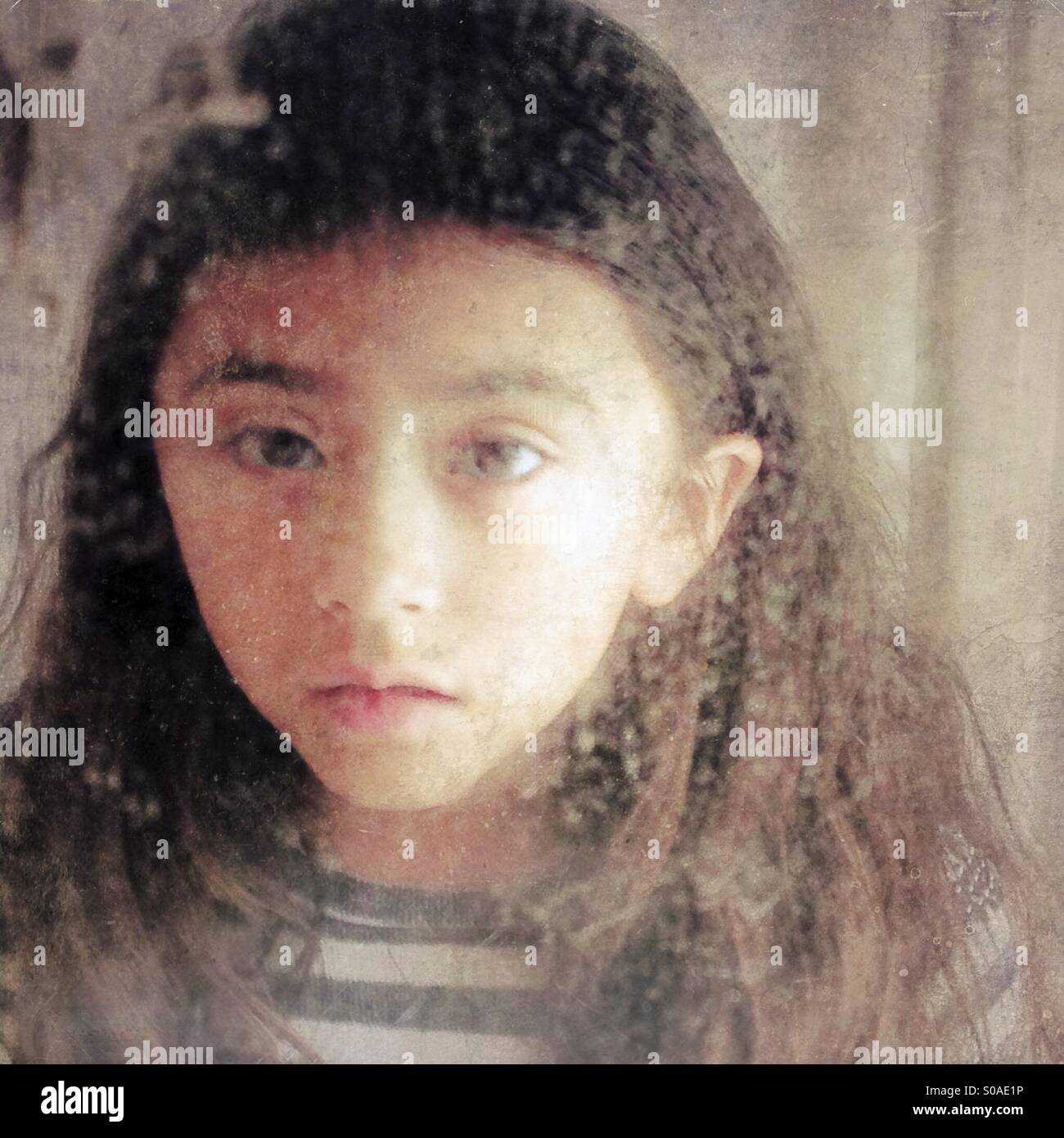 La réflexion d'une petite fille à la recherche dans un vieux miroir à la triste ou malade. Banque D'Images