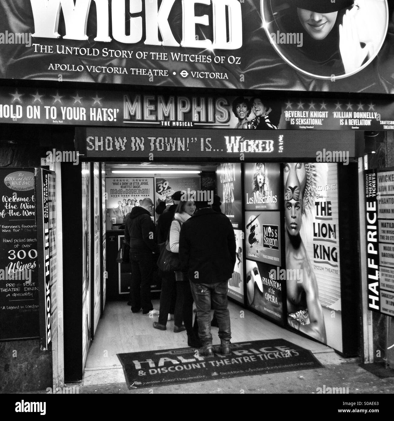 Image en noir et blanc de personnes en attente pour les billets de théâtre à un kiosque dans Leicester Square, Londres Banque D'Images