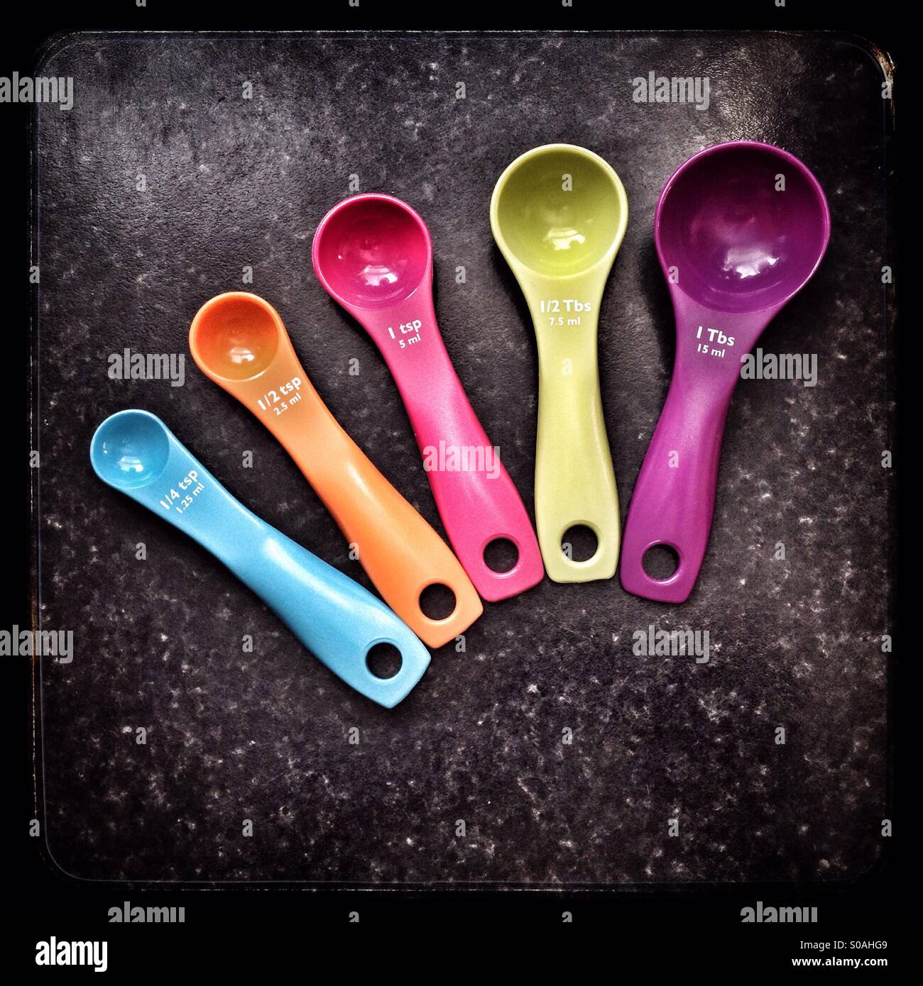 Couleur 5 cuillères à mesurer par rapport à une surface de travail en marbre noir. - Image de stock capturée avec un smartphone