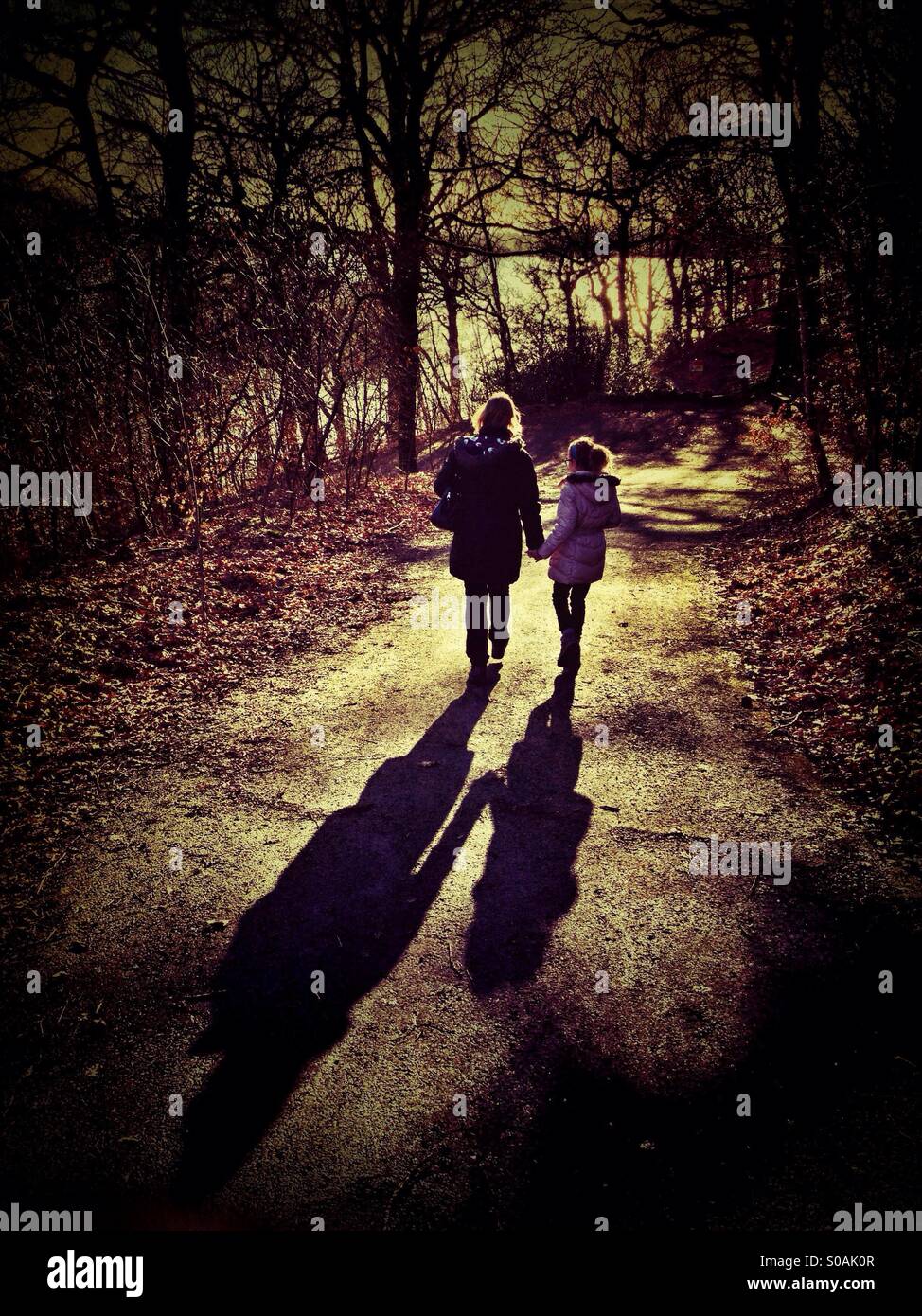 Mère et fille marcher main dans la main vers le bas chemin Pays de longues ombres casting Banque D'Images