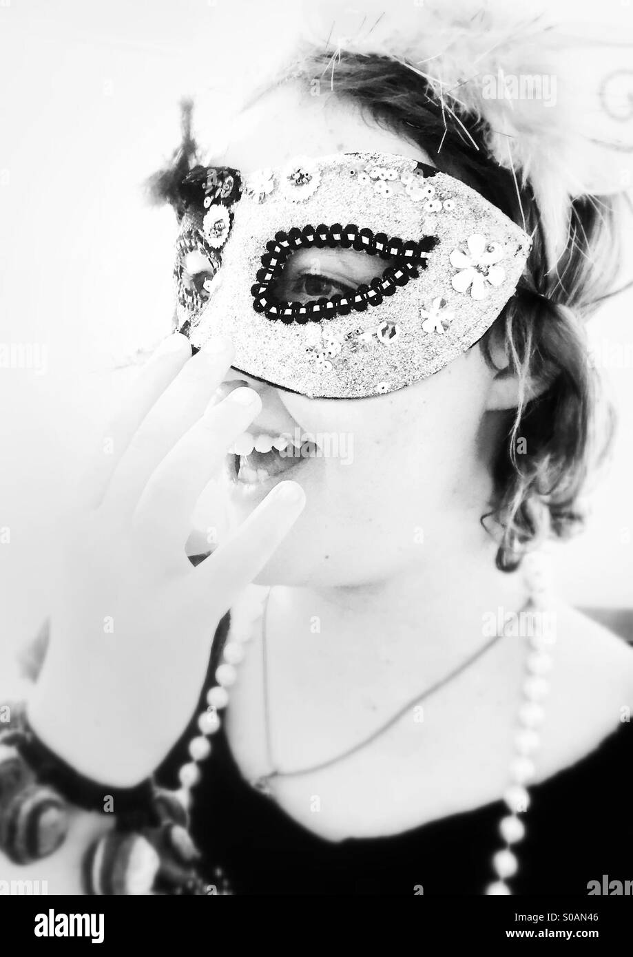 Girl wearing masquerade mask et rire - noir et blanc Banque D'Images