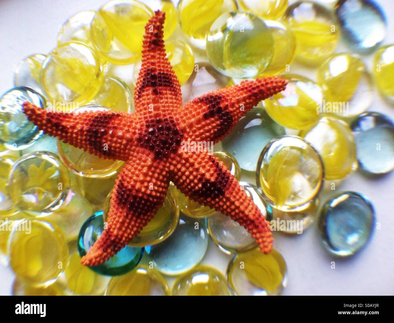 Orange jouet étoile sur un tas de cailloux en verre jaune Banque D'Images