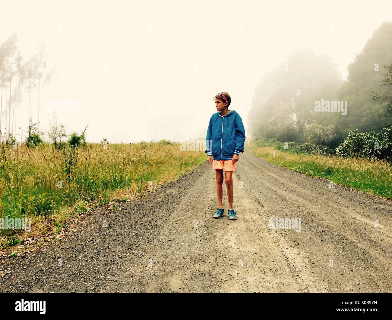 Un garçon de onze ans marchant dans un pays sur la voie d'un jour brumeux Banque D'Images