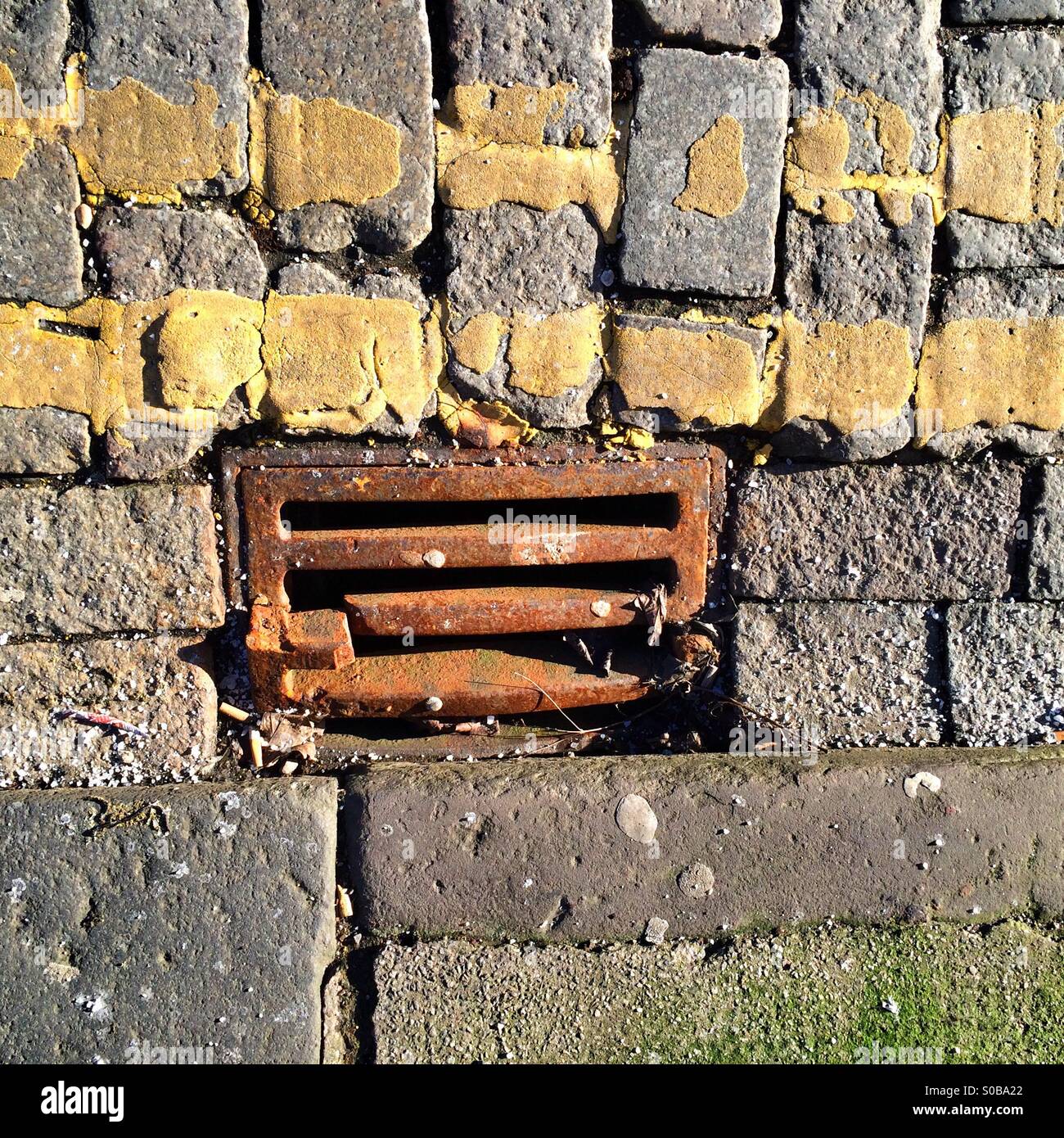 Grille de caniveau en fonte cassée sur le côté d'une route à double lignes jaunes - Image de stock capturée avec un smartphone