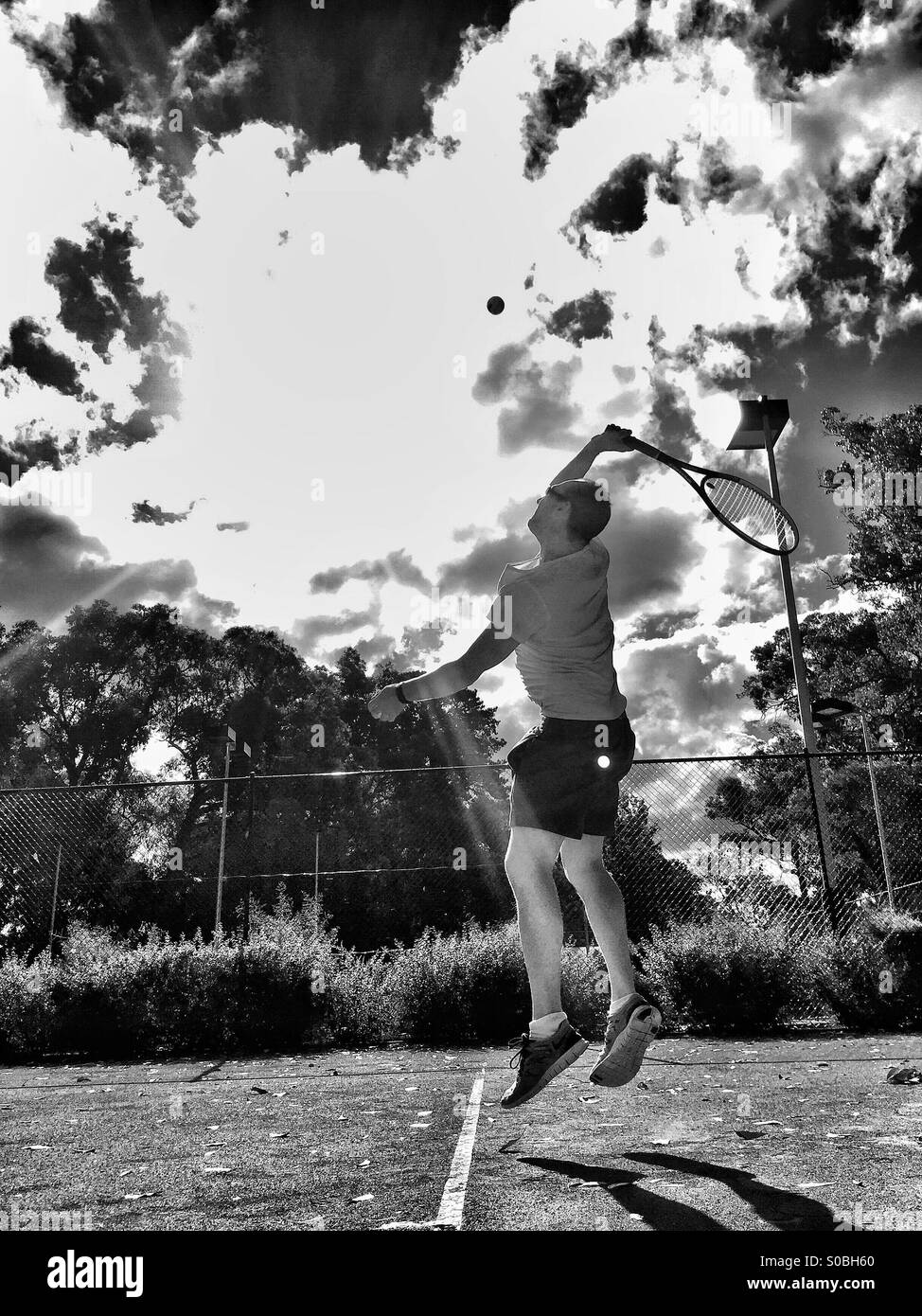 L'homme au service d'une balle de tennis - action tourné en noir et blanc Banque D'Images