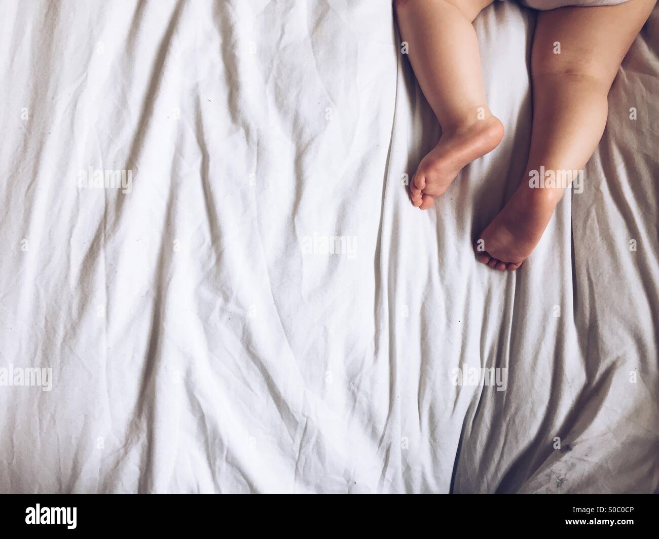 Image de jambes du bébé alors qu'elle est endormie sur le lit Banque D'Images