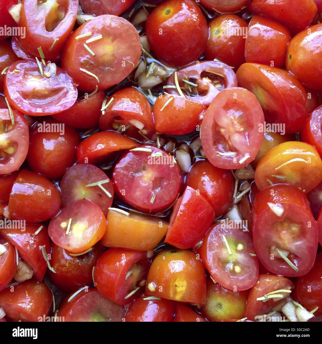 Couper les tomates raisins avec de l'huile d'olive, le vinaigre balsamique, l'ail et le romarin-ingrédients pour une sauce pour pâtes simples. Banque D'Images