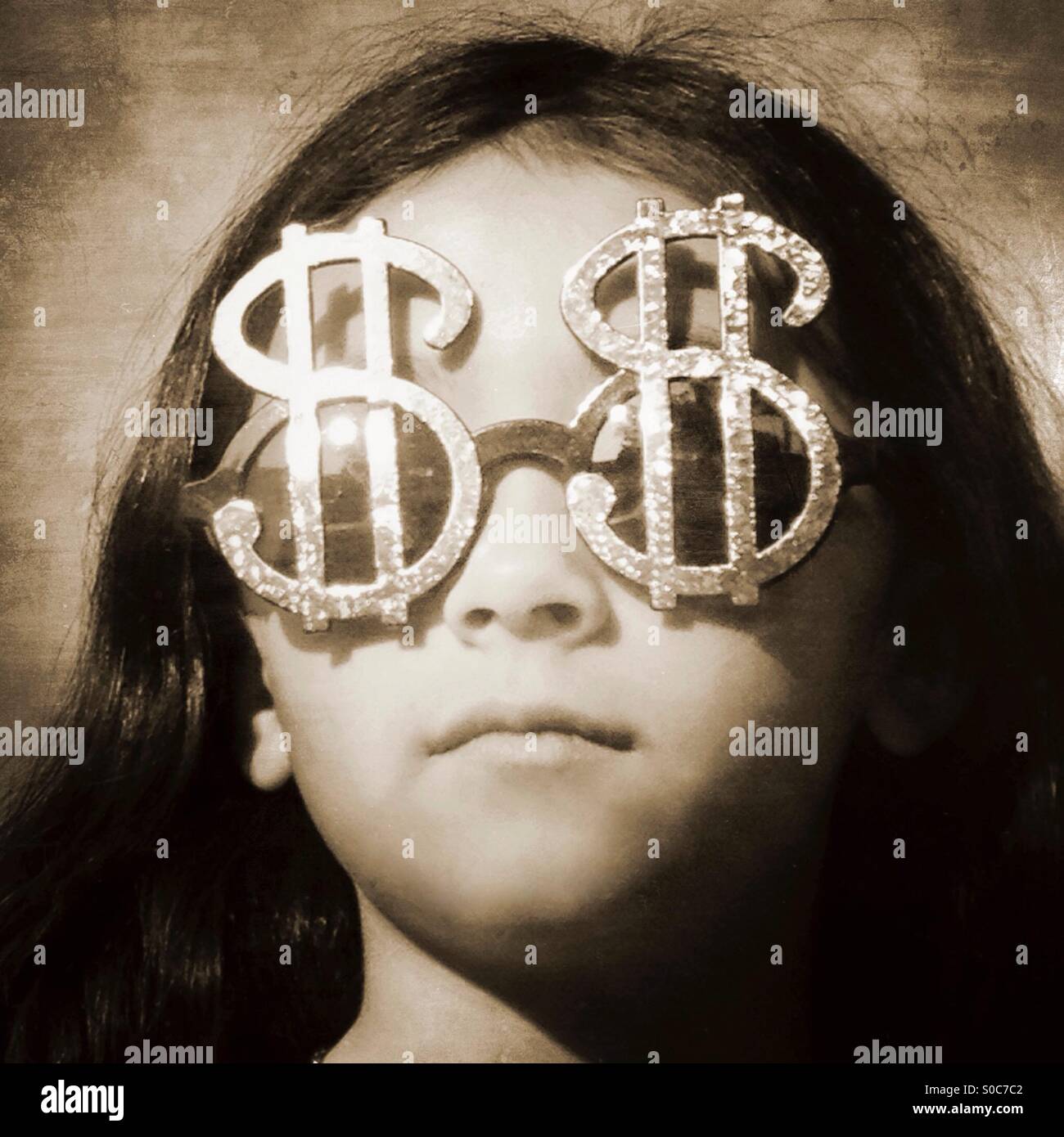 Petite fille portant des lunettes en forme de signes dollar. Banque D'Images