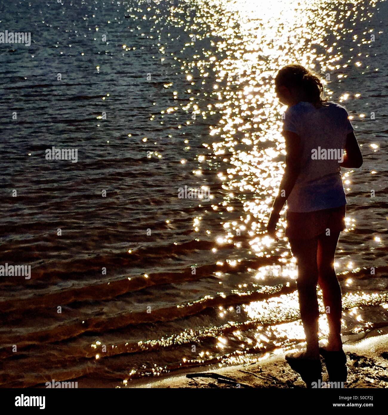 Girl au bord de la mer au coucher du soleil Banque D'Images