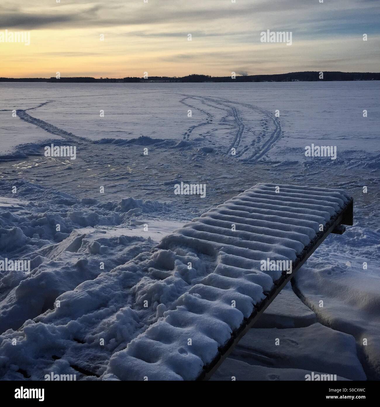 Une patinoire, un quai et des pistes de ski au coucher du soleil à un endroit idyllique lac gelé de l'Arctique en hiver en Scandinavie Banque D'Images