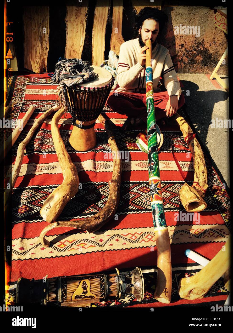 Jeune homme sur un tapis pendant la lecture d'une flûte de pan entouré d'éléments ethniques Banque D'Images