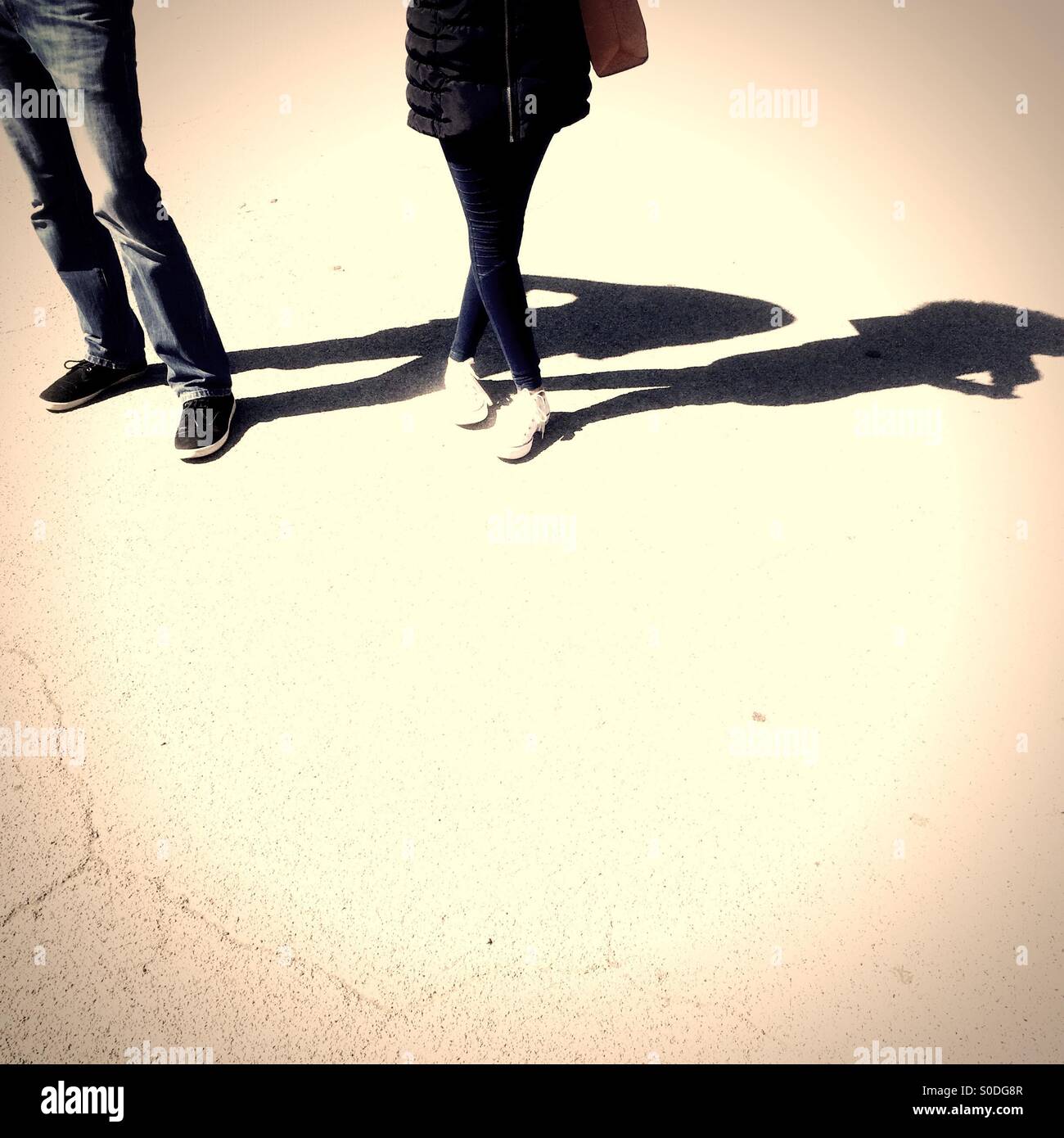 Couple debout sur le béton sur journée ensoleillée à l'ombre qui plane Banque D'Images