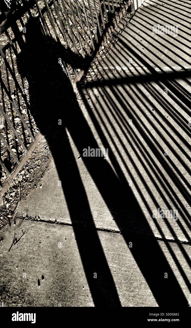 Longtemps, de grands ombres d'une personne debout par une clôture Banque D'Images
