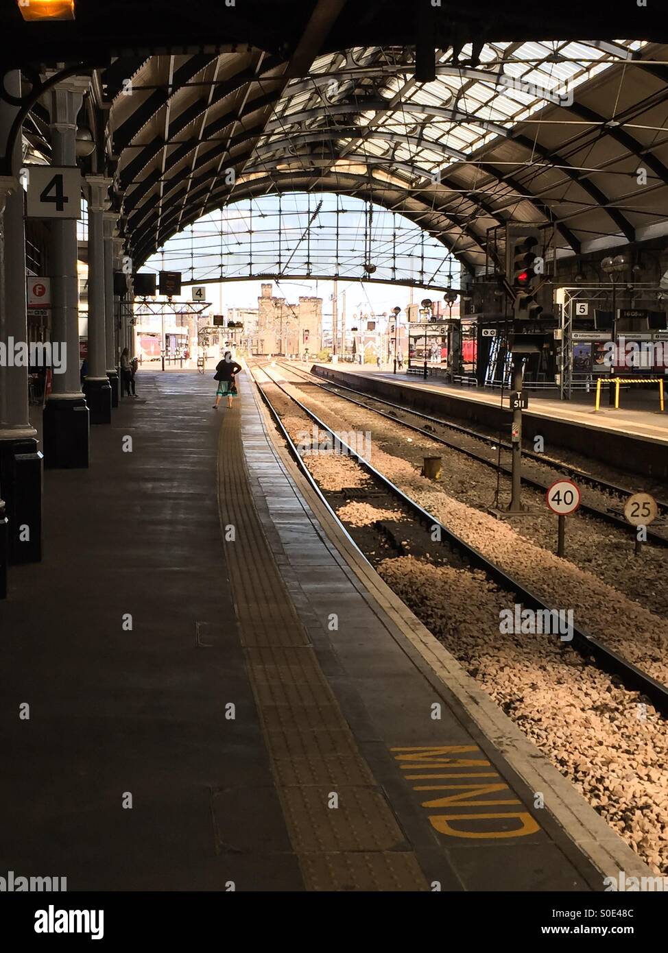 Seul un passager féminin en attente d'un train à la gare centrale de Newcastle upon Tyne et Wear Angleterre Royaume-Uni UK Banque D'Images