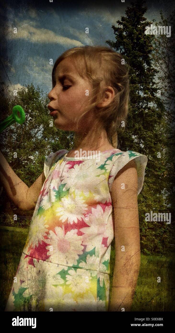 Une fille jouant avec des bulles dans la cour (1). Banque D'Images
