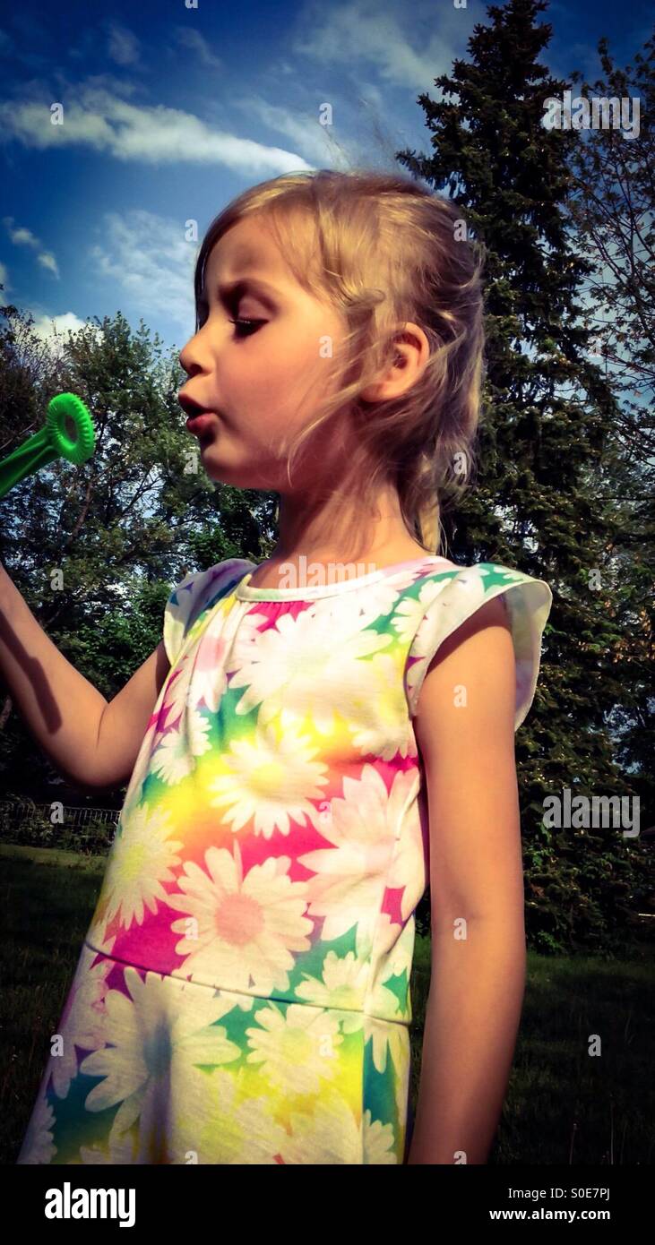Une fille jouant avec des bulles dans la cour (2). Banque D'Images