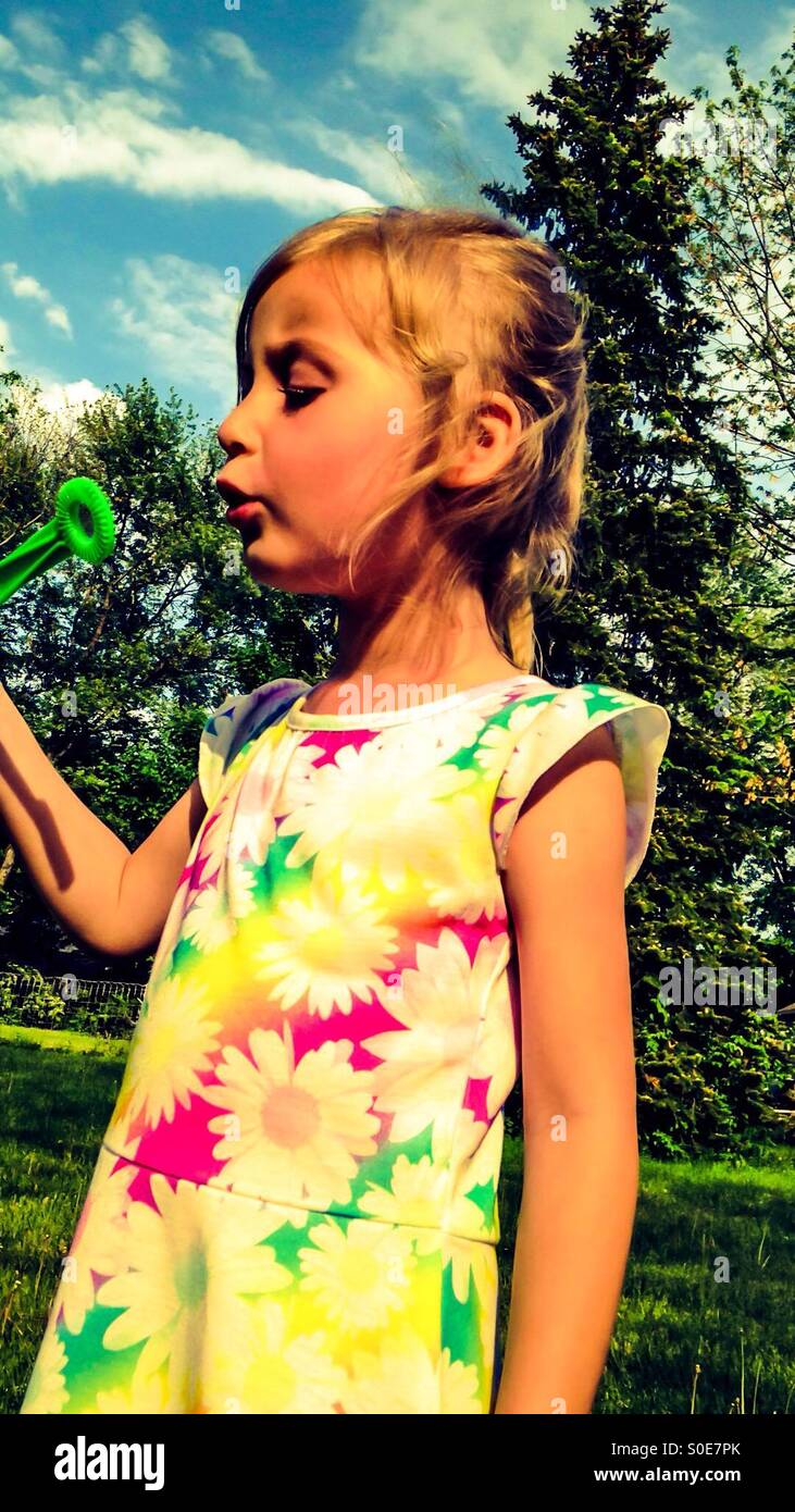 Une fille jouant avec des bulles dans la cour (3). Banque D'Images