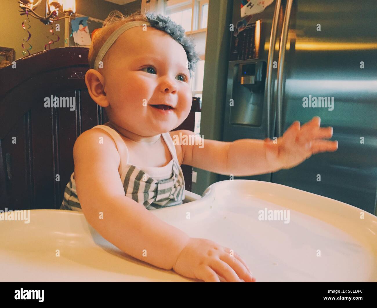 Baby Girl, souriant et jouant dans une chaise haute Banque D'Images