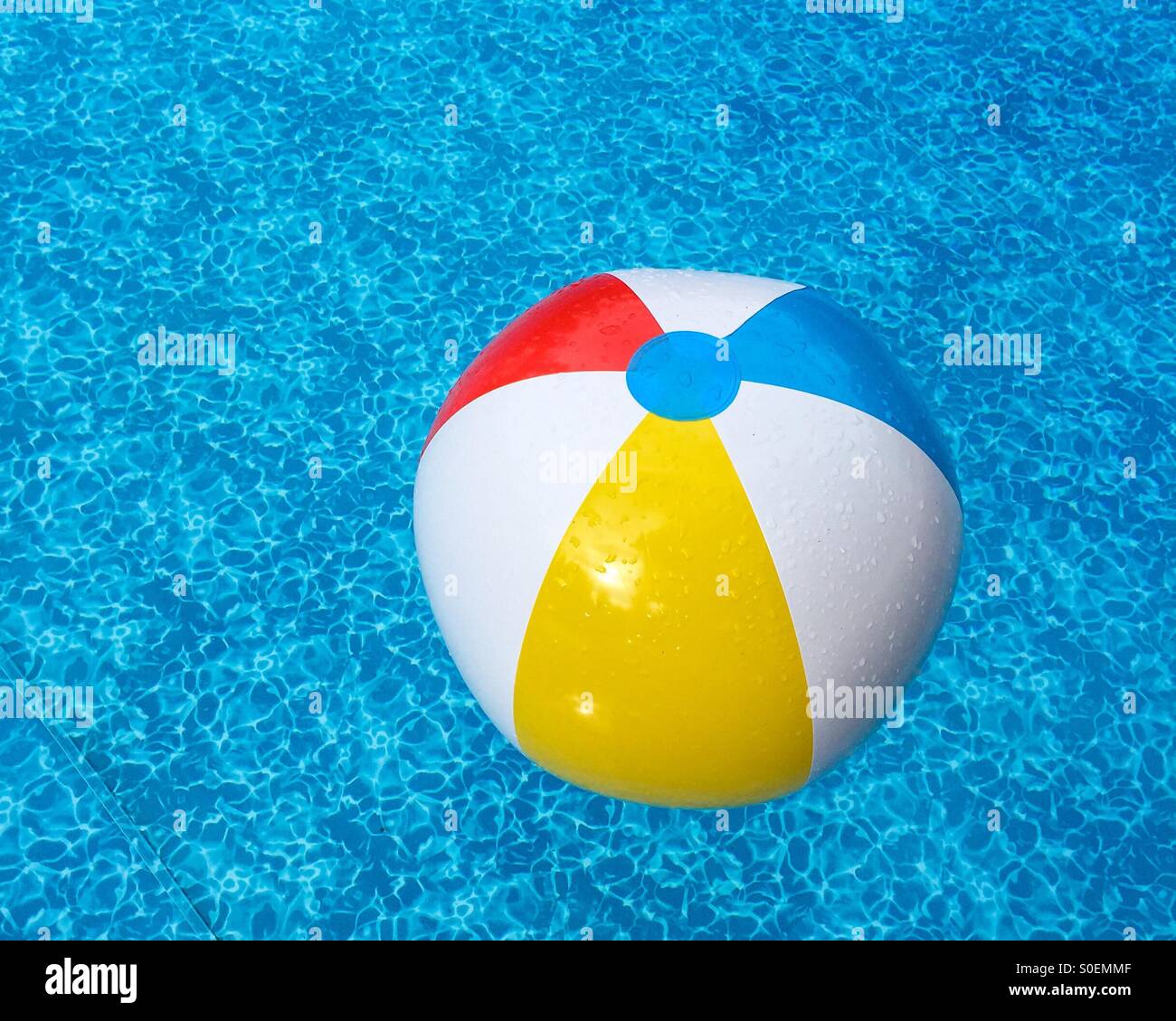 Beach ball flottant dans les eaux bleues de la piscine. Banque D'Images