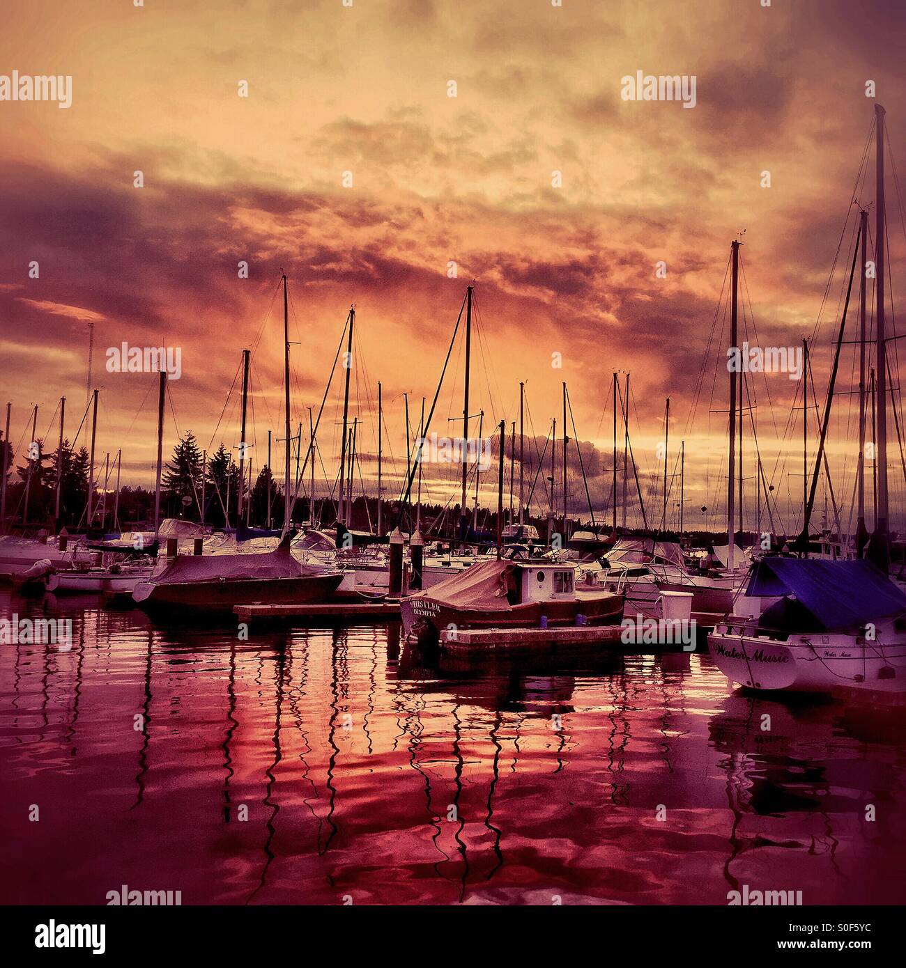 Couleurs glorieuses dans le ciel et se reflètent dans l'eau entourent certains bateaux dans un port du nord-ouest du Pacifique au coucher du soleil. Banque D'Images