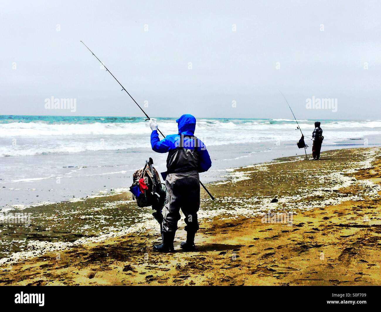Deux pêcheurs locaux travaillant leurs tiges et bobines sur une longue étendue de plage de la Californie du Nord. - Image de stock capturée avec un smartphone